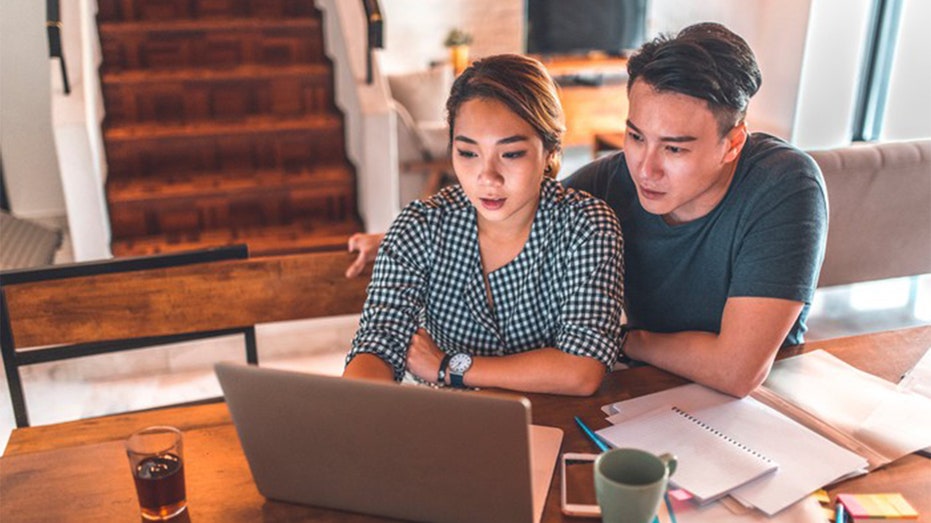 Two people sitting at a table with a laptop 