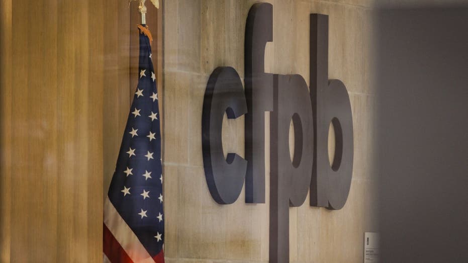Consumer Financial Protection Bureau sign on wall next to an American flag