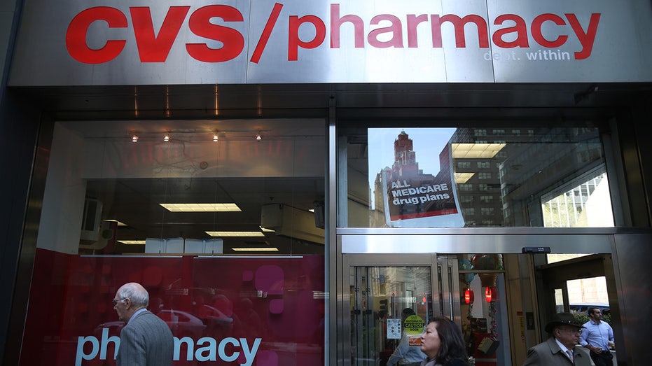 CVS pharmacy sign above entrance to store with people walking past