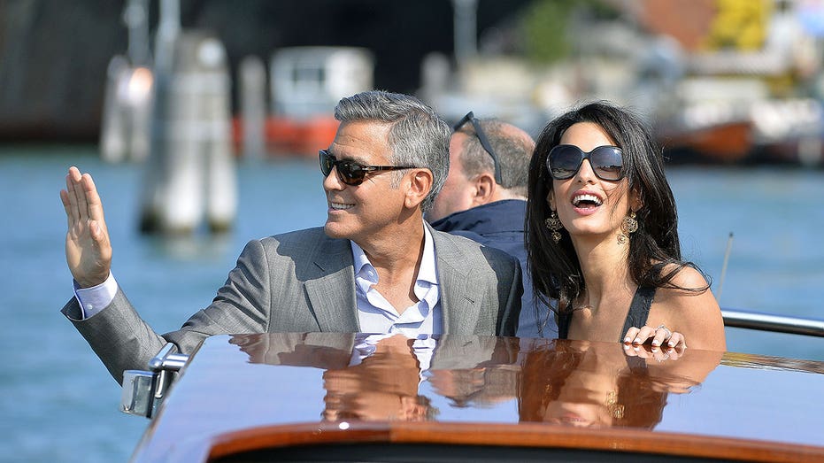 George Clooney waves and Amal Alamuddin take a taxiboat upon their arrival in Venice