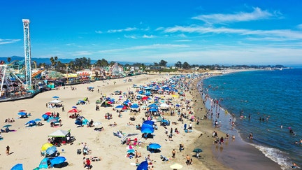 Visitors pack the beach in front of the Santa Cruz Beach Boardwalk in Santa Cruz, Calif., on a summer day. The coastal city has been ranked the least affordable rental market in the U.S., according to the National Low Income Housing Coalition’s 2025 report. - Fox Business News