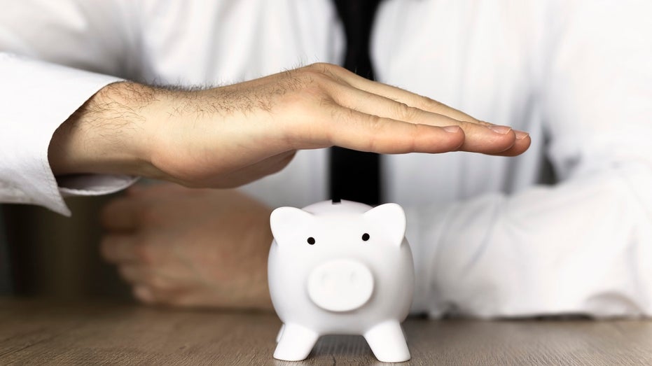businessman with hand over piggy bank